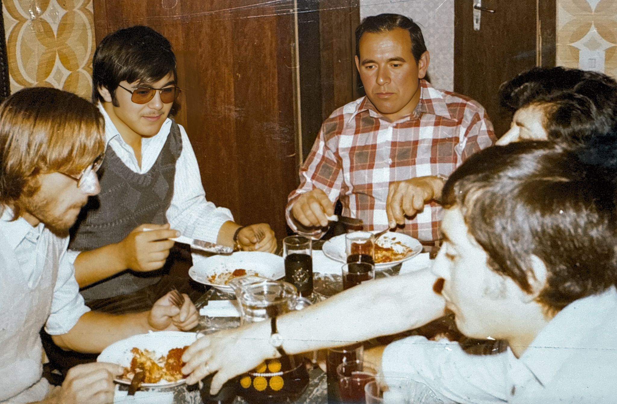 A family gathered around a table sharing a meal, an old photograph